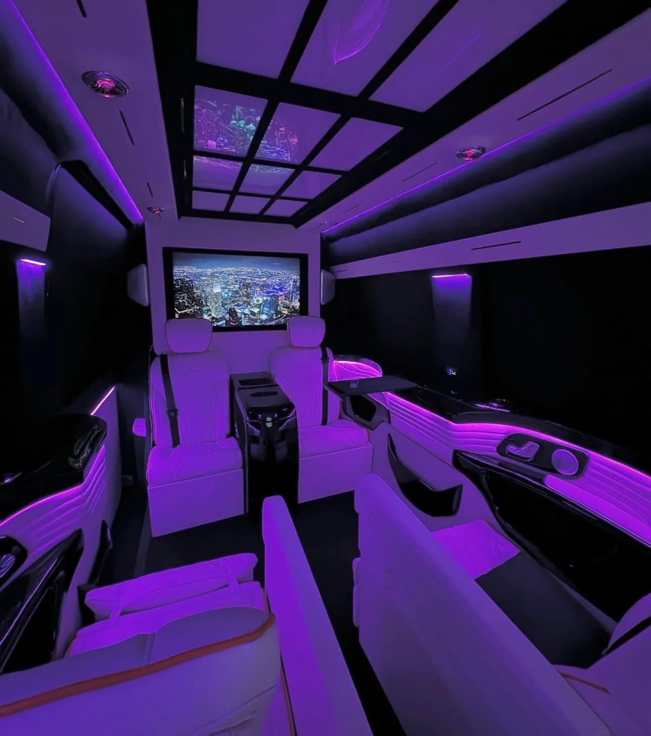 Luxury Sprinter VIP cabin with purple ambient lighting, club seating and TV
