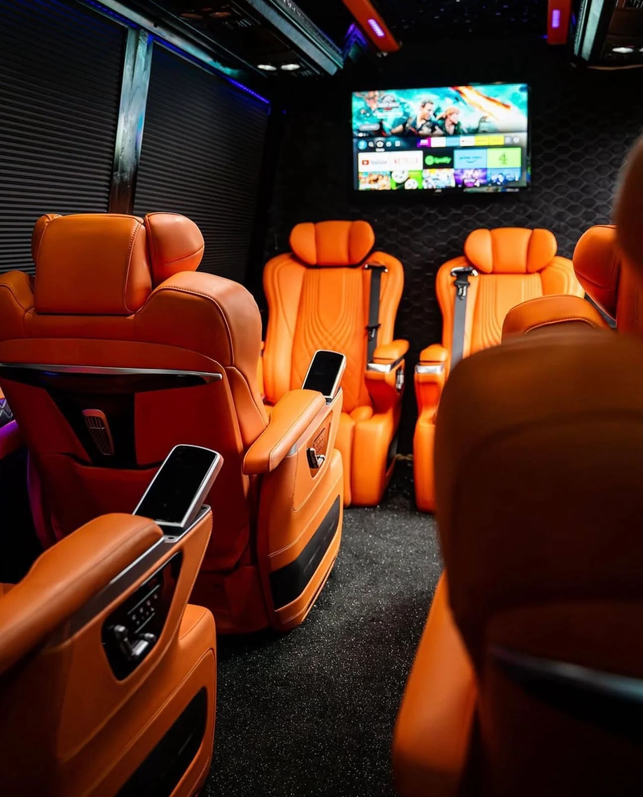 Luxury van interior with orange leather captain chairs and rear entertainment screen