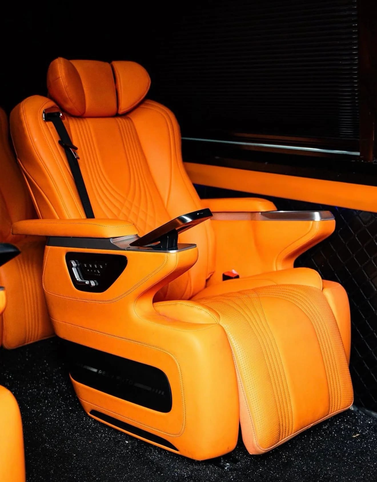 Orange leather captain chair with controls in a luxury VIP van
