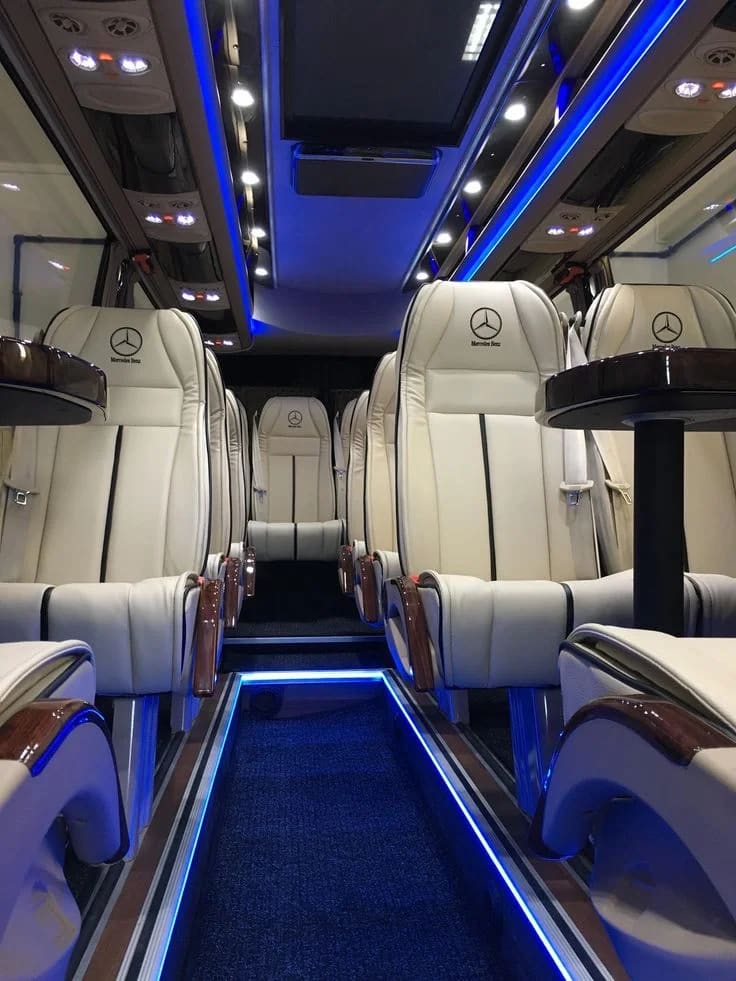 Mercedes luxury minibus interior with white leather seats and blue ambient lighting