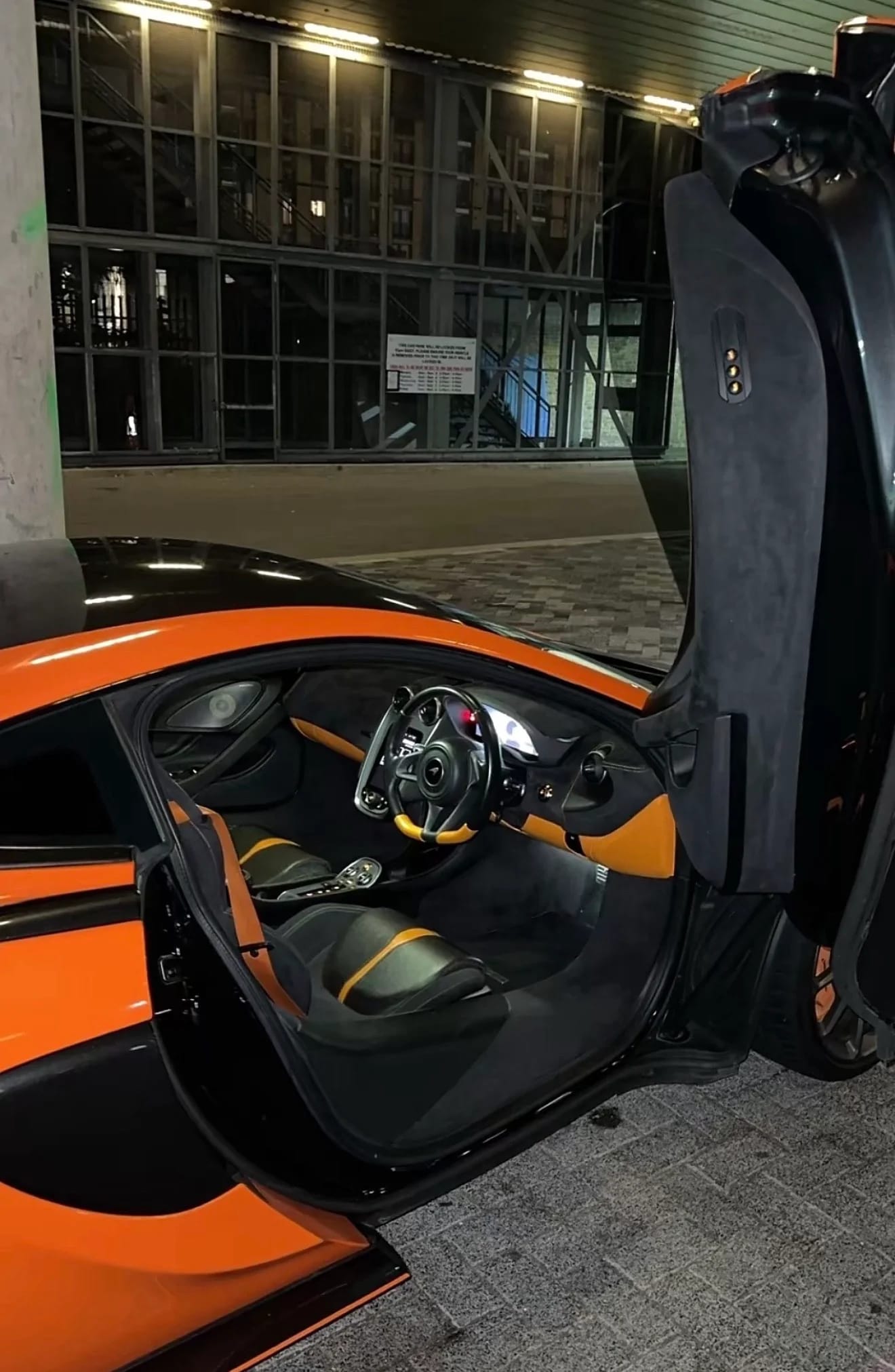 Orange McLaren supercar interior with butterfly door open at night